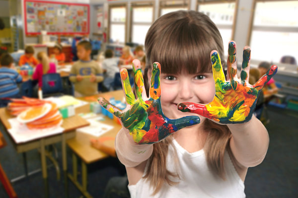 Niña con manos pintadas en el aula